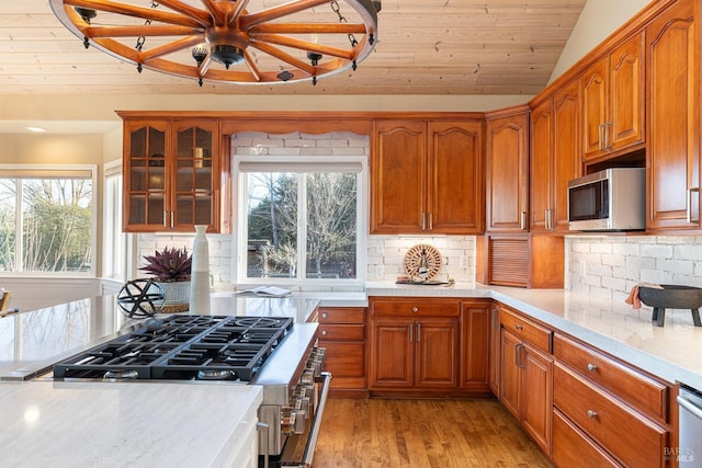 kitchen featuring stainless steel appliances, light countertops, vaulted ceiling, light wood-type flooring, and plenty of natural light