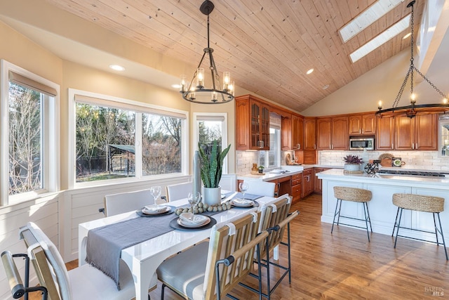 dining space featuring vaulted ceiling with skylight, recessed lighting, wood ceiling, and light wood-style floors