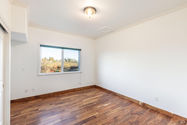 empty room featuring baseboards, ornamental molding, and wood finished floors