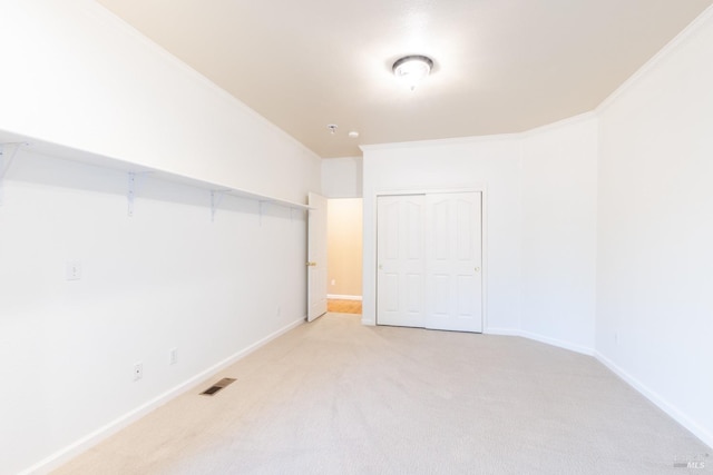 spare room featuring ornamental molding, light colored carpet, visible vents, and baseboards