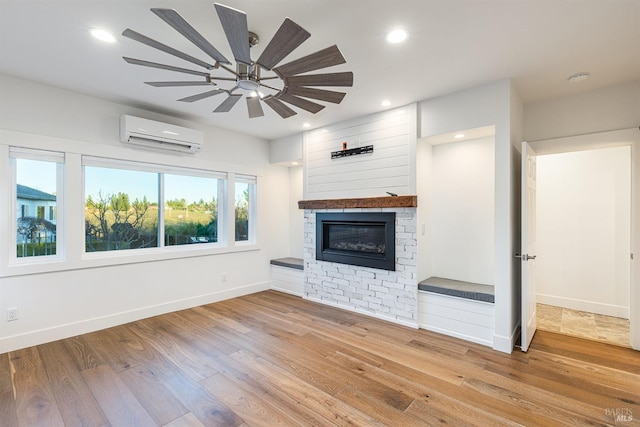 unfurnished living room with recessed lighting, a fireplace, an AC wall unit, and wood finished floors