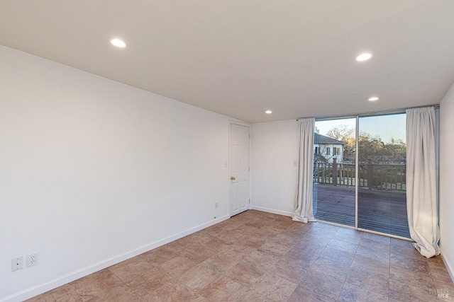 unfurnished room with recessed lighting, floor to ceiling windows, and baseboards