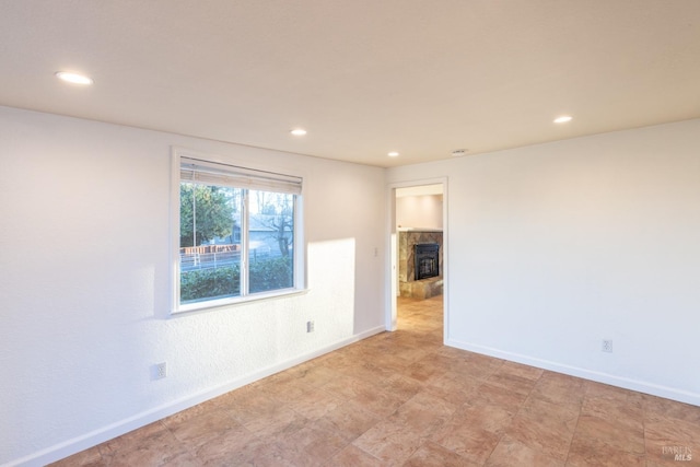 empty room featuring recessed lighting, a fireplace, and baseboards