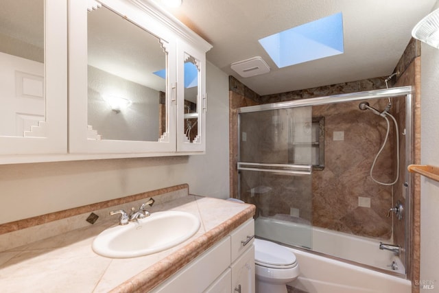 bathroom with shower / bath combination with glass door, a skylight, vanity, and toilet