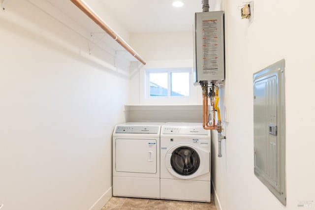 washroom featuring tankless water heater, washing machine and dryer, laundry area, baseboards, and electric panel