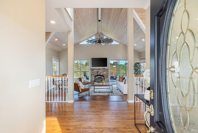 entrance foyer featuring ceiling fan, high vaulted ceiling, wooden ceiling, a fireplace, and wood finished floors