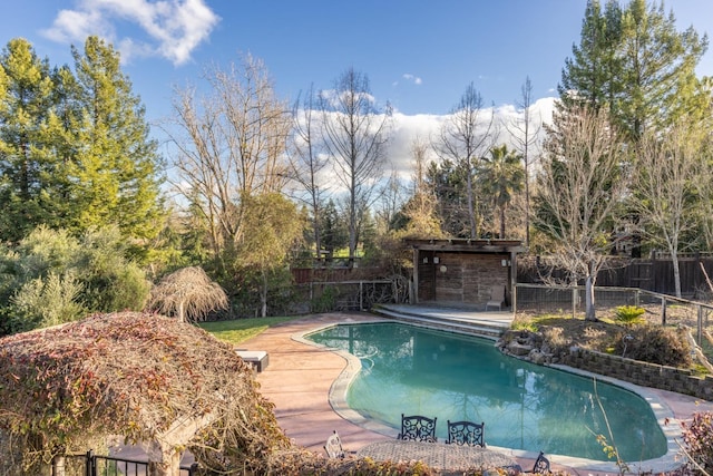 view of swimming pool with a patio area, an outdoor structure, a fenced backyard, and a fenced in pool