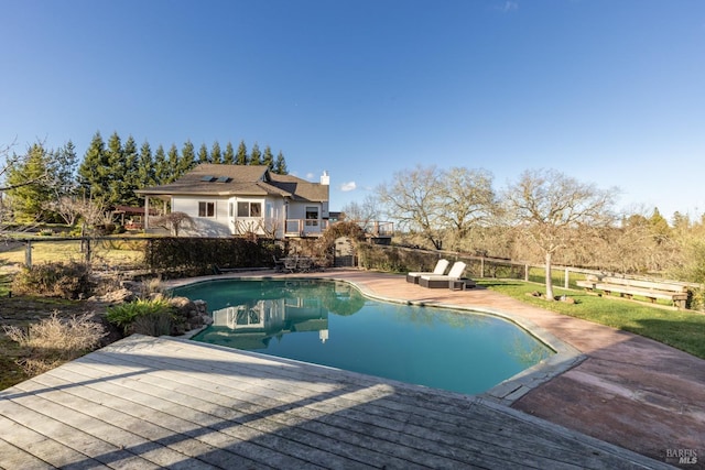 pool with fence, a wooden deck, and a patio