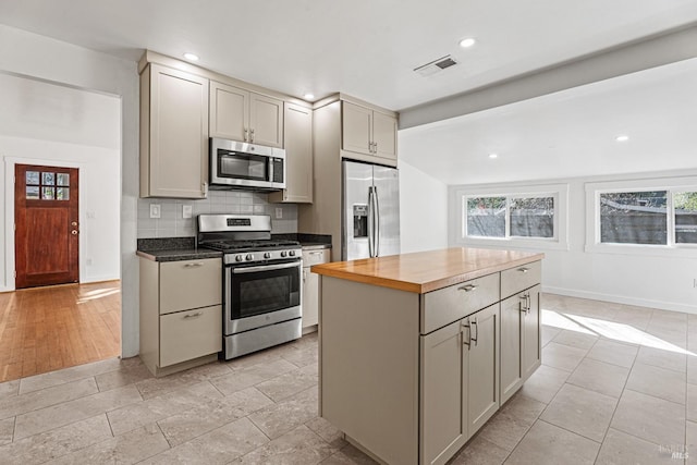 kitchen with stainless steel appliances, plenty of natural light, wooden counters, and backsplash