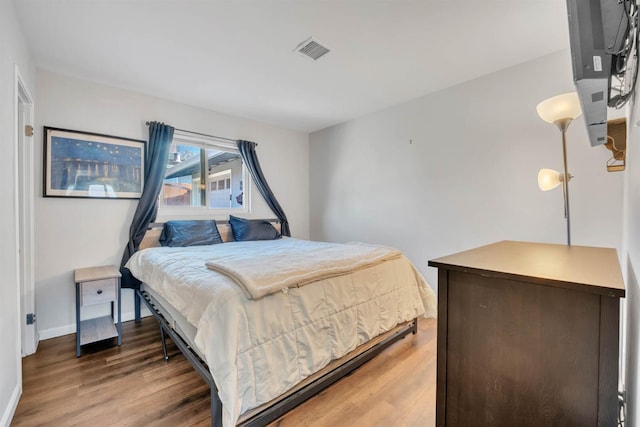 bedroom featuring baseboards, wood finished floors, and visible vents