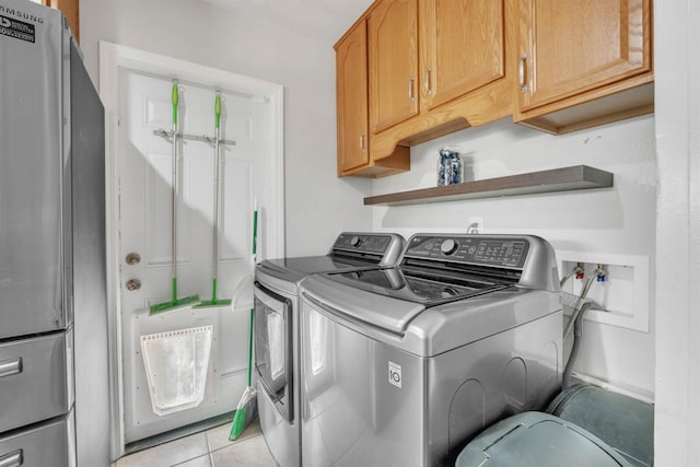 washroom with washing machine and dryer, cabinet space, and light tile patterned floors