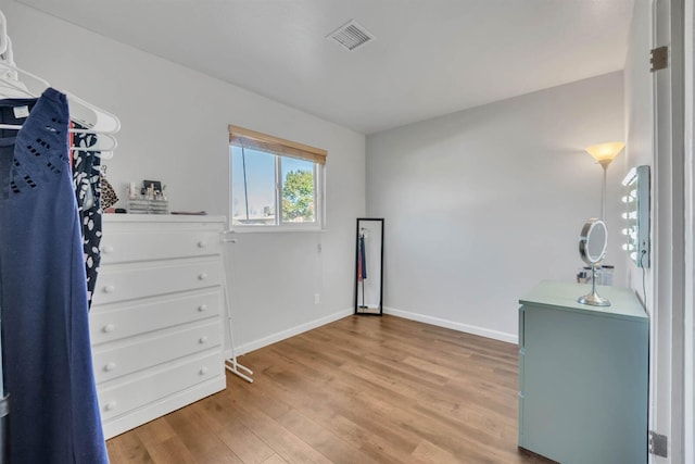 bedroom with wood finished floors, visible vents, and baseboards