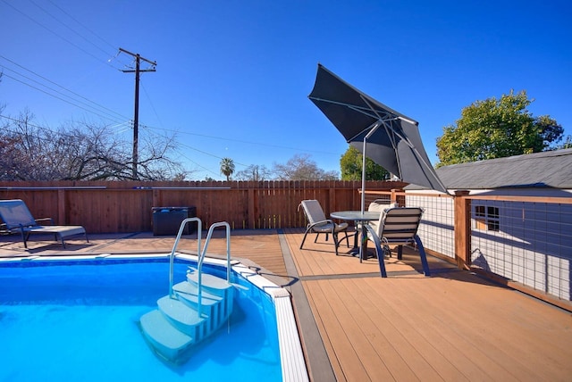 view of swimming pool featuring a wooden deck, a fenced in pool, outdoor dining space, and fence