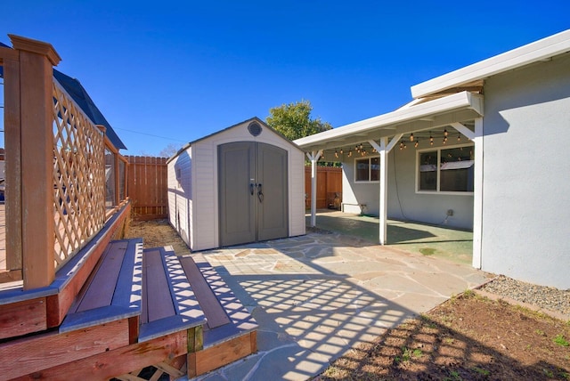 view of patio featuring a fenced backyard, an outdoor structure, and a storage unit
