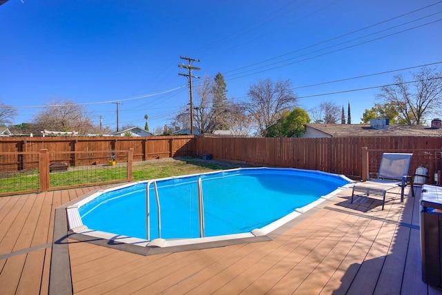view of swimming pool featuring a wooden deck, a fenced backyard, and a fenced in pool