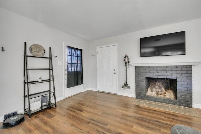 unfurnished living room featuring dark hardwood / wood-style flooring and a brick fireplace