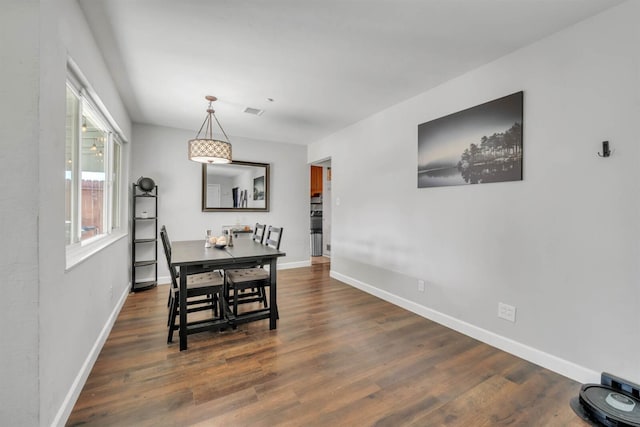 dining space with wood finished floors, visible vents, and baseboards