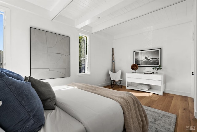 bedroom featuring hardwood / wood-style floors and beam ceiling