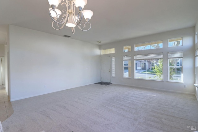 spare room with visible vents, carpet flooring, baseboards, and a notable chandelier