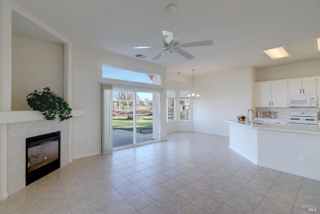 kitchen featuring a tile fireplace, light countertops, a sink, white appliances, and ceiling fan with notable chandelier