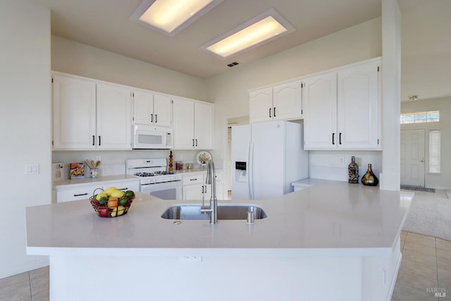 kitchen with light tile patterned flooring, white cabinetry, sink, kitchen peninsula, and white appliances