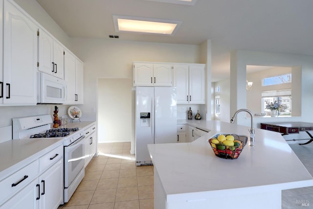 kitchen with white cabinetry, light tile patterned floors, white appliances, and kitchen peninsula