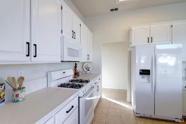 kitchen with white appliances, white cabinets, and light tile patterned flooring