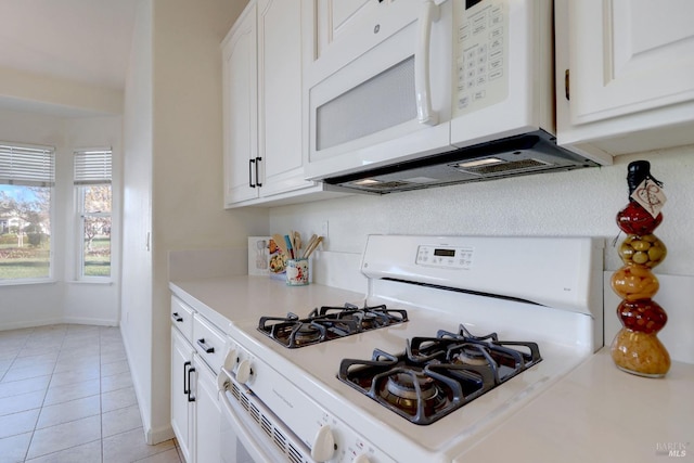 kitchen with white appliances, light tile patterned floors, and white cabinets