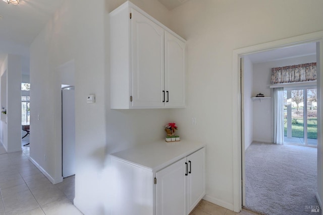 hallway with light tile patterned flooring, a healthy amount of sunlight, and baseboards