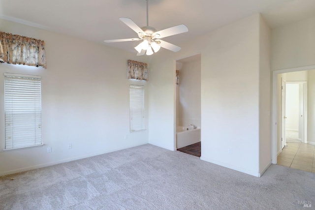 carpeted empty room featuring baseboards and a ceiling fan