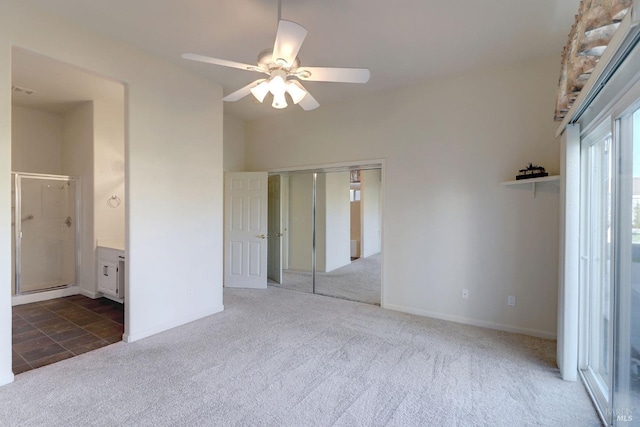 unfurnished bedroom featuring dark carpet, a closet, ceiling fan, and ensuite bathroom