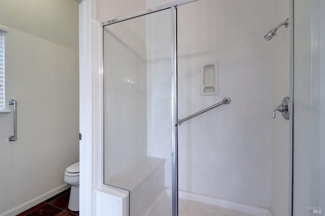bathroom featuring baseboards, toilet, and a stall shower