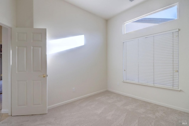 empty room featuring baseboards and light carpet