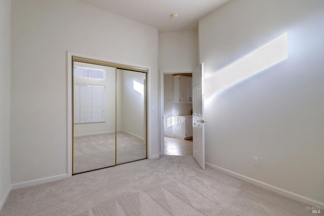 unfurnished bedroom with a closet, light carpet, and a high ceiling