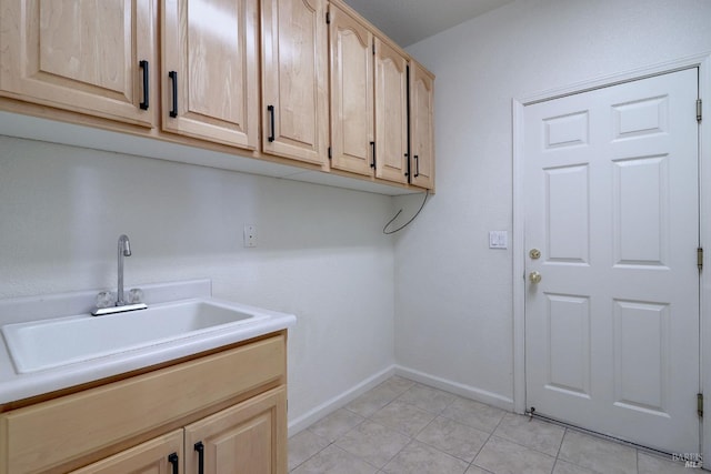 clothes washing area with light tile patterned flooring, baseboards, and a sink