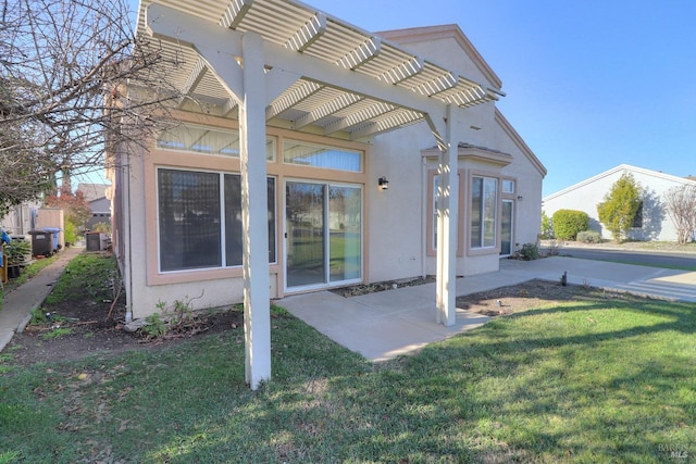 back of house with a pergola, a yard, a patio area, and stucco siding