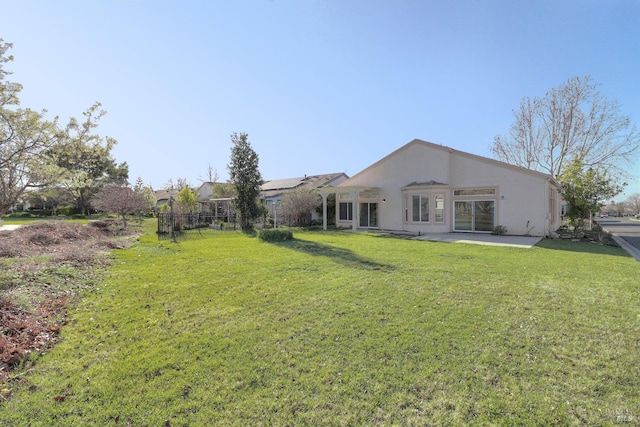 back of property with a yard, a patio area, stucco siding, and fence