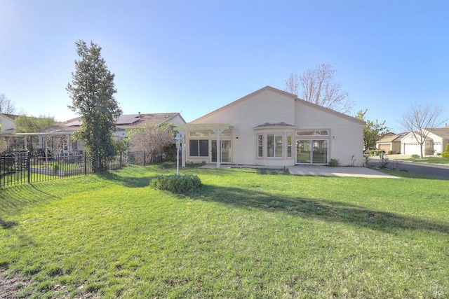 rear view of house with a yard, a patio area, stucco siding, and fence