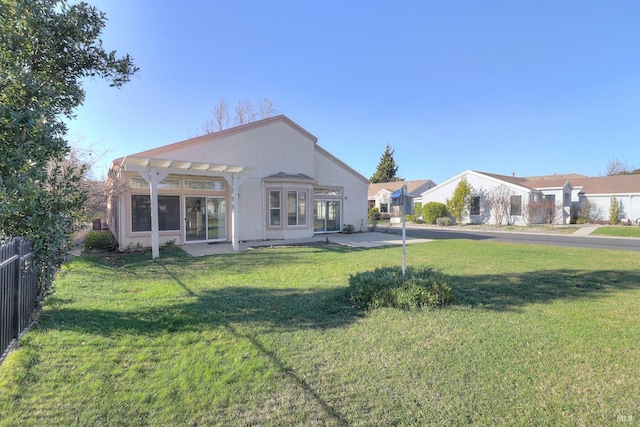 rear view of property featuring stucco siding, fence, a yard, and a pergola