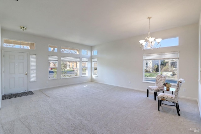 sitting room featuring an inviting chandelier, light colored carpet, and a high ceiling