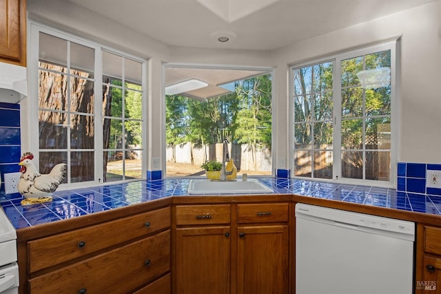 kitchen featuring tile countertops, white dishwasher, a sink, and brown cabinets