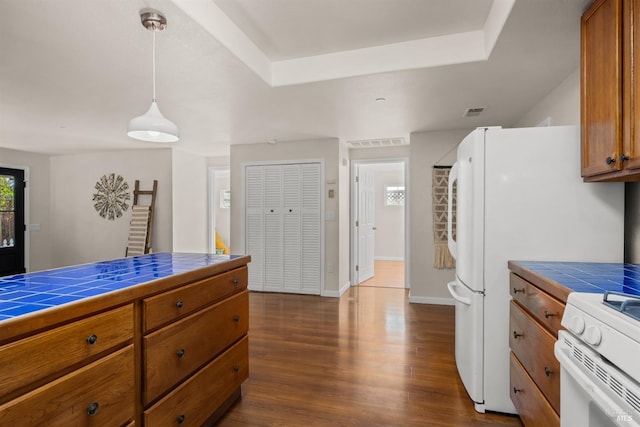 kitchen featuring visible vents, brown cabinetry, tile counters, and decorative light fixtures