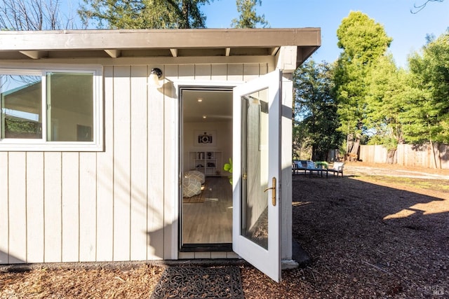 entrance to property featuring fence and board and batten siding