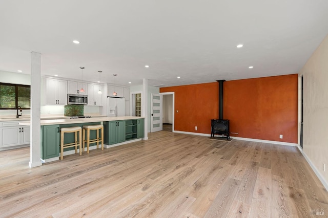 kitchen featuring light countertops, stainless steel microwave, white cabinetry, white fridge with ice dispenser, and green cabinetry