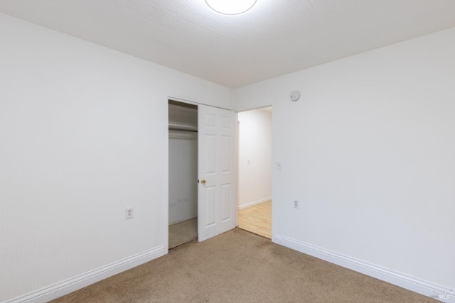 unfurnished bedroom with light carpet and a closet