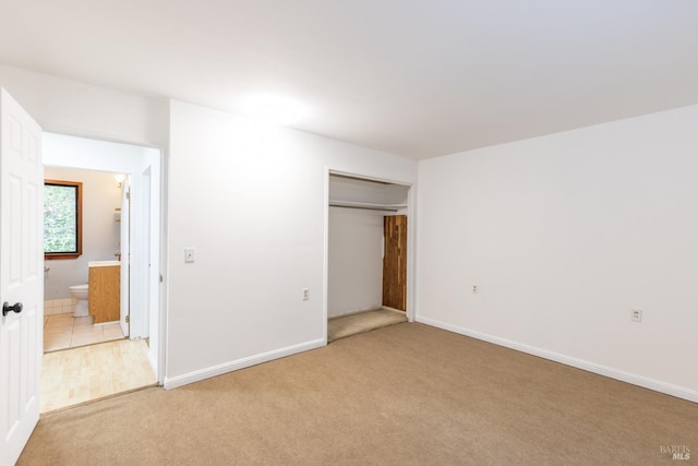 unfurnished bedroom with light colored carpet and a closet