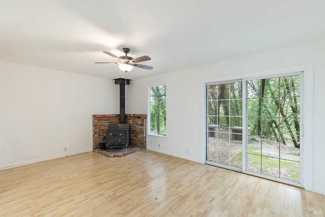 unfurnished living room featuring light hardwood / wood-style flooring, ceiling fan, and a wood stove