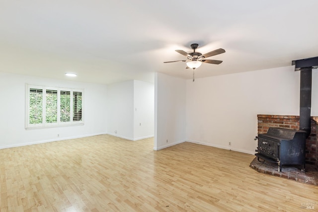 unfurnished living room featuring ceiling fan, light hardwood / wood-style floors, and a wood stove