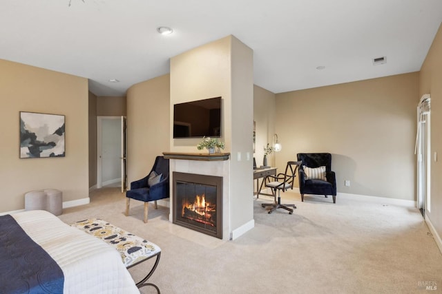 bedroom featuring a tiled fireplace and light carpet