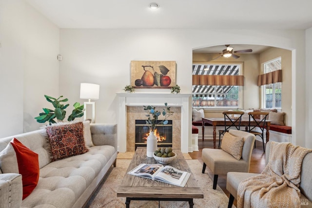 living room with a fireplace, ceiling fan, and light wood-type flooring